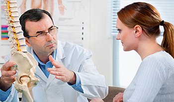 Chiropractor explaining spine and hip alignment to a patient during consultation